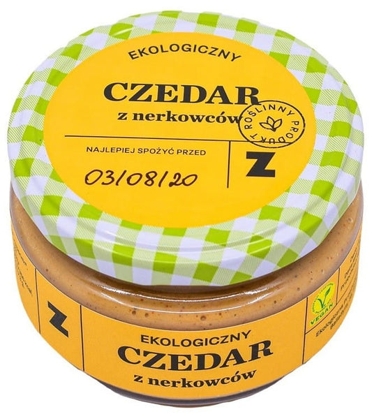 Bio Cheddar mit Cashewnüssen von ZAKWASOWNIA in 200 g Packung, cremiger Käse mit nussigen Cashewstücken, orangefarben.